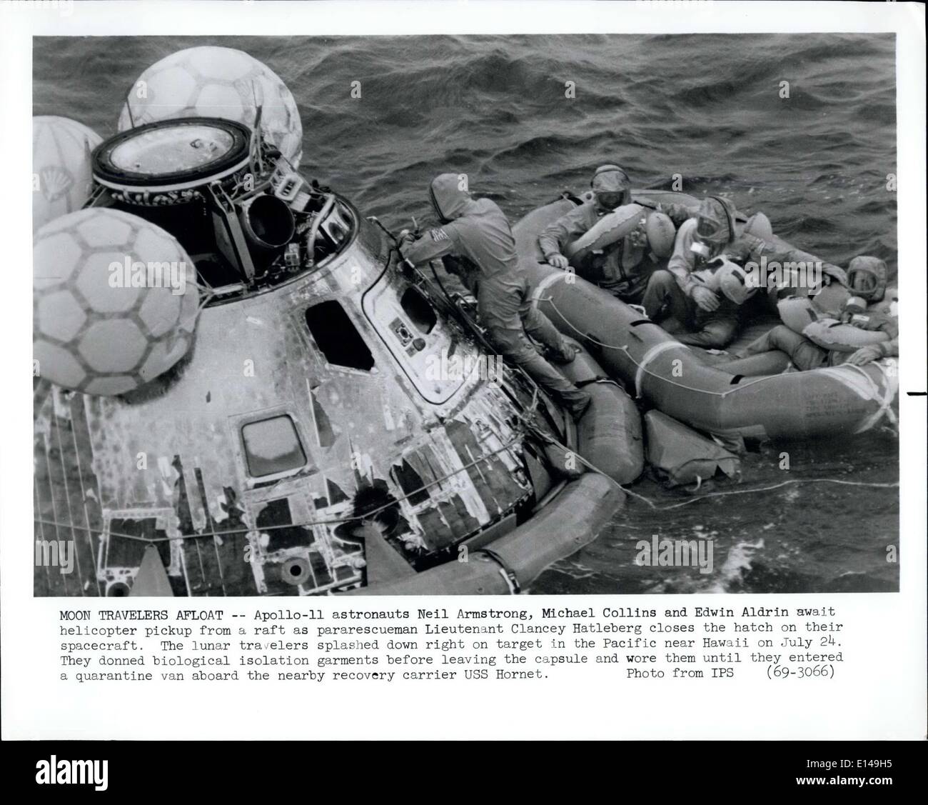 Apr. 17, 2012 - Moon Travellers Afloat -- Apollo-11 astronauts Neil Armstrong, Michael Collins and Edwin Aldrin await helicopter pick-up from a raft as pararescueman Lieutenant Clancey Hatleberg closes the hatch on their spacecraft. The lunar travellers splashed down right on target in the Pacific near Hawaii on July 24. They donned biological isolation garments before leaving the capsule and wore them until they entered a quarantine van aboard the nearby recovery carrier USS Hornet. Stock Photo