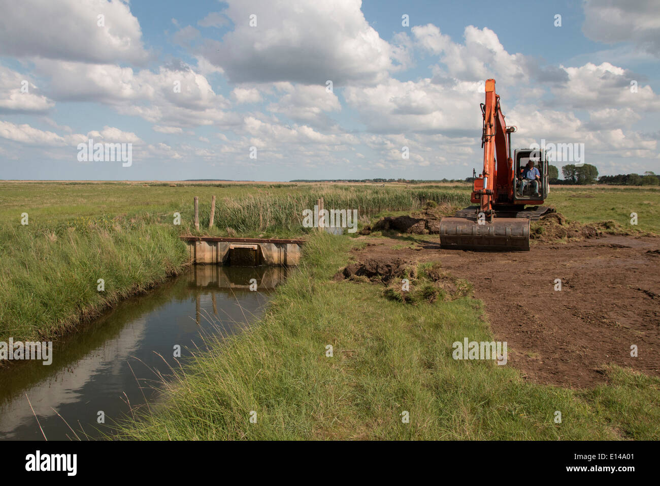 Using a digger for maintenance work on sluice gate at Deepdale Marsh north Norfolk. Stock Photo