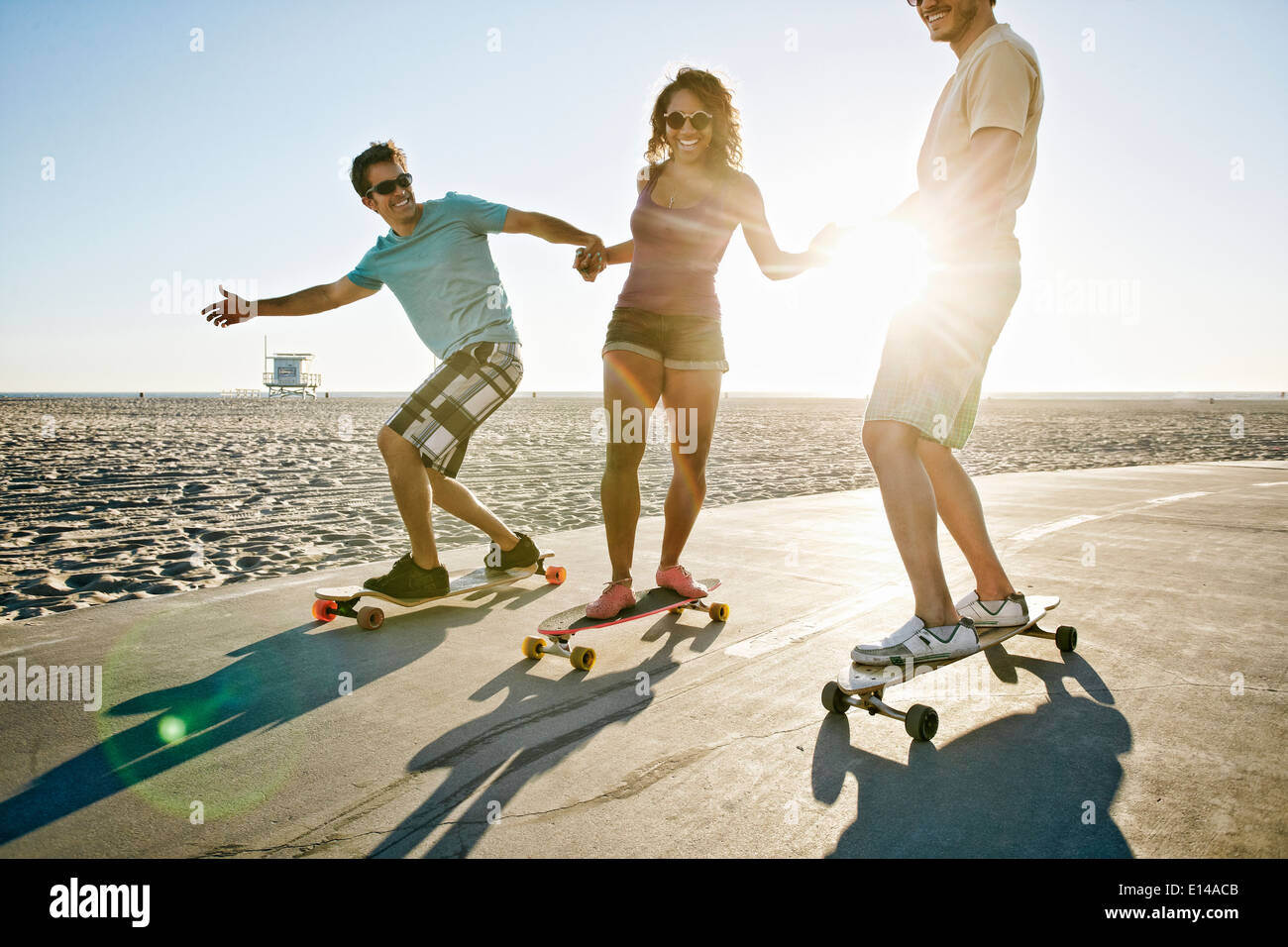 Friends riding longboards on beach Stock Photo