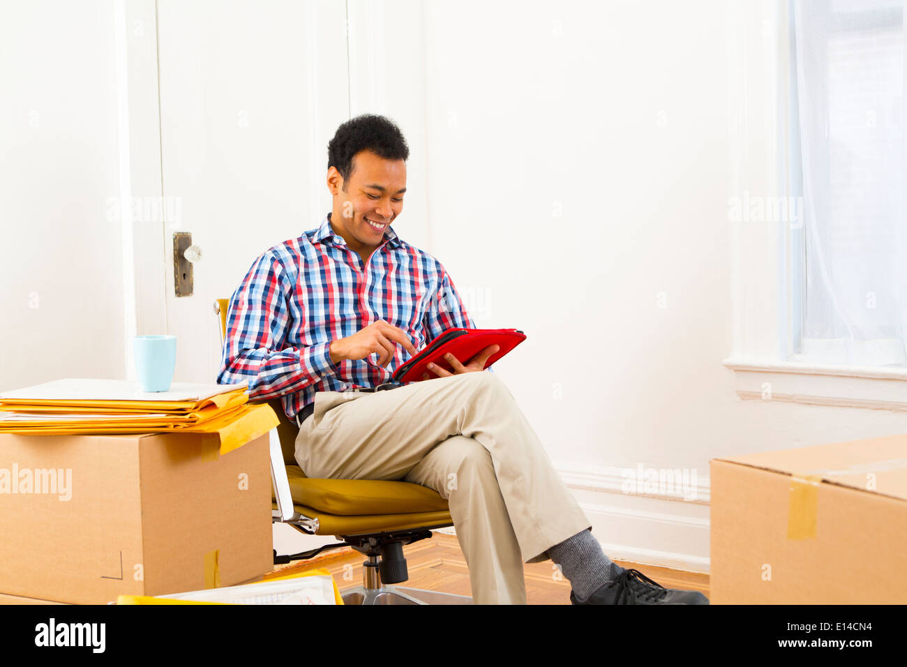Mixed race man using digital tablet in new home Stock Photo