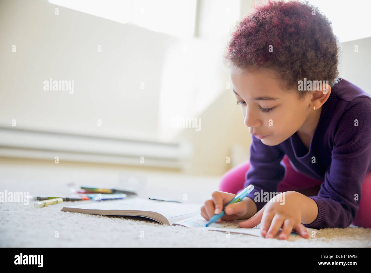 Mixed race girl coloring on floor Stock Photo