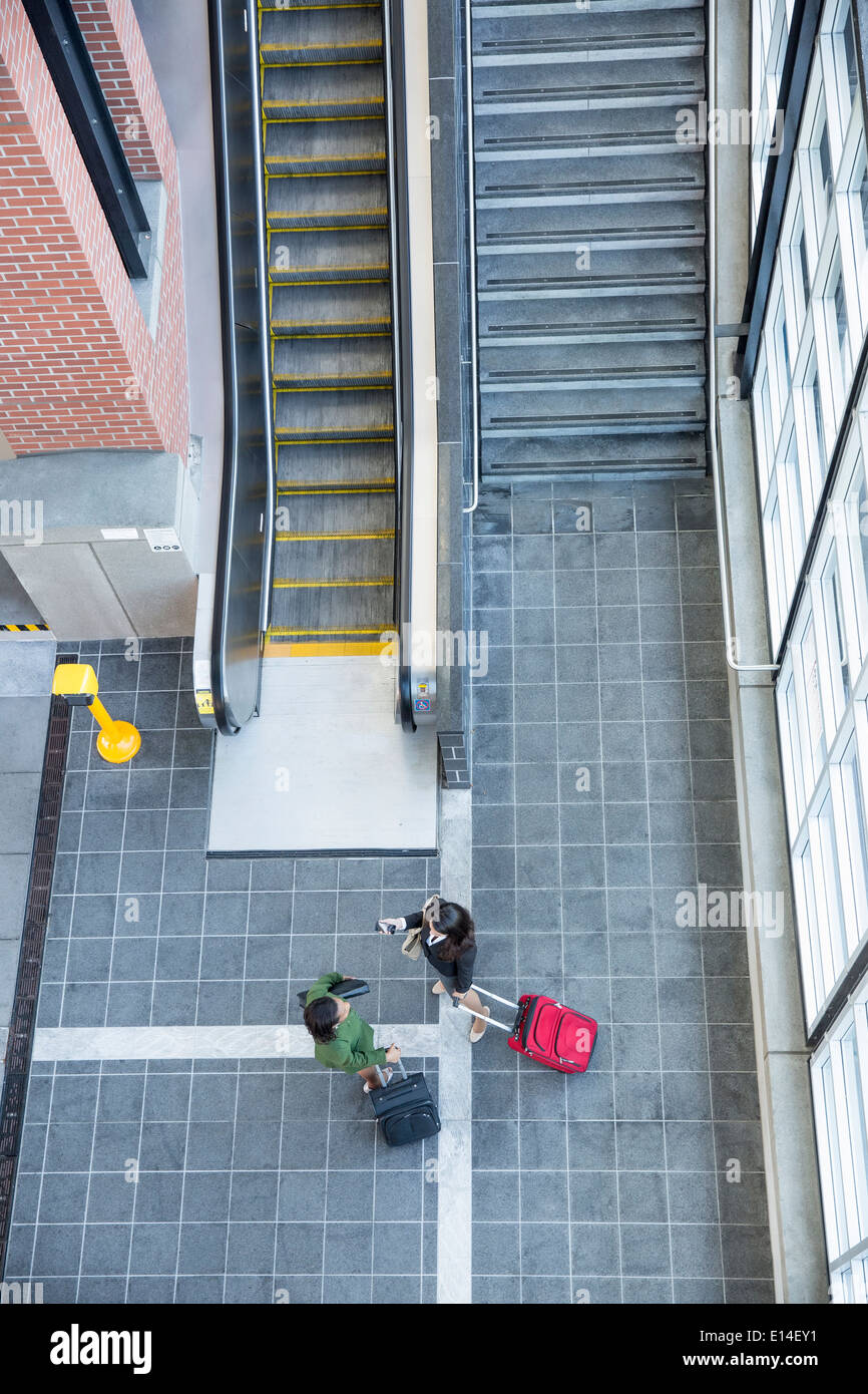 Businesswomen talking near stairs and escalator Stock Photo