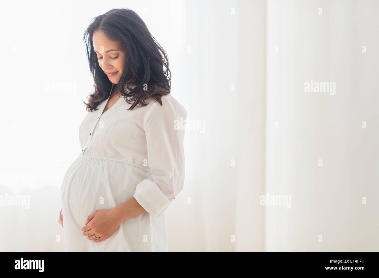 Pregnant hispanic woman touching belly hi-res stock photography