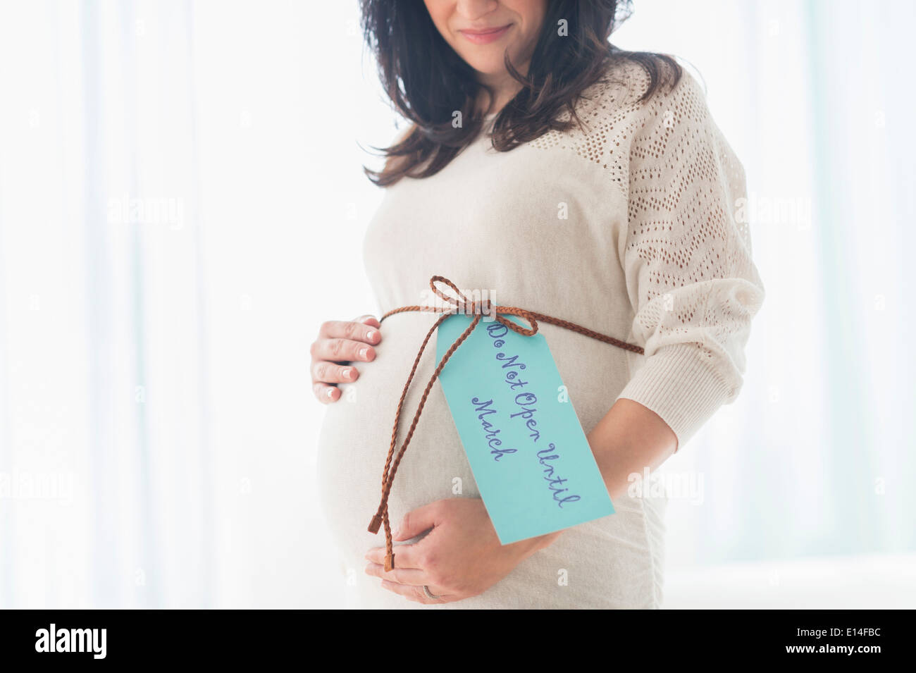 Pregnant Hispanic woman with gift wrap around belly Stock Photo