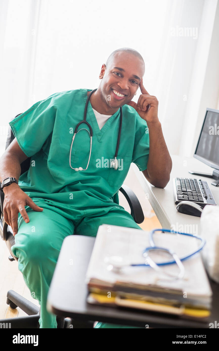Black doctor smiling at computer in office Stock Photo