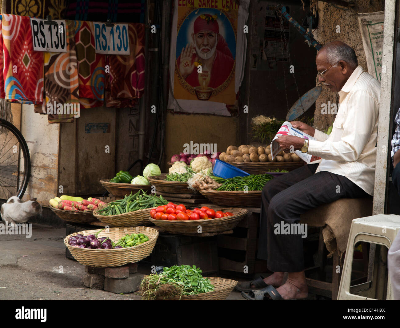 India, Mumbai, Fort District, Parsi Bazaar, vegetable vendor reading Hindi language newspaper Stock Photo