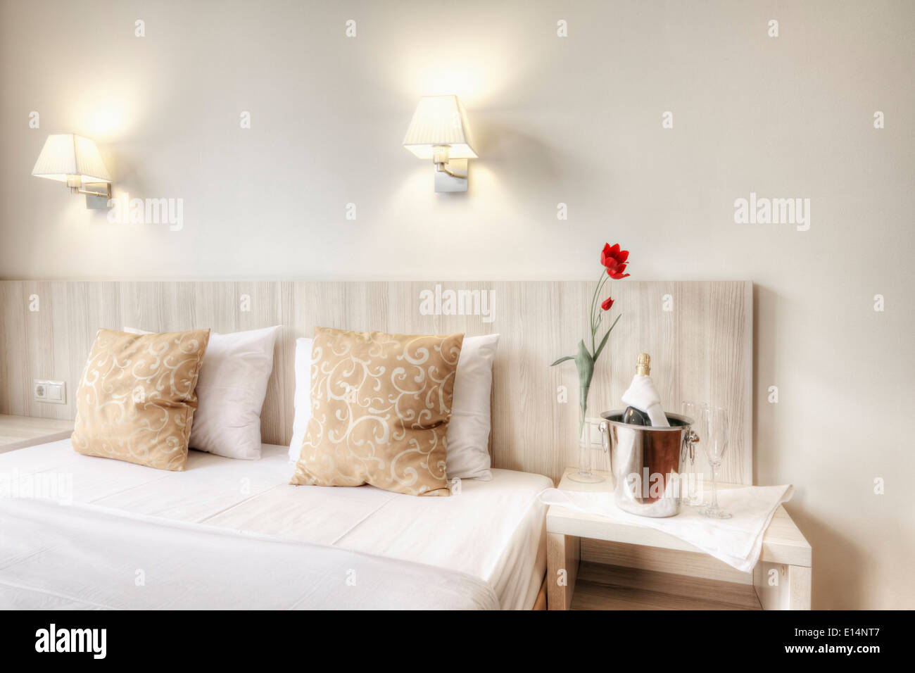 Champagne and glasses by bed in hotel room Stock Photo