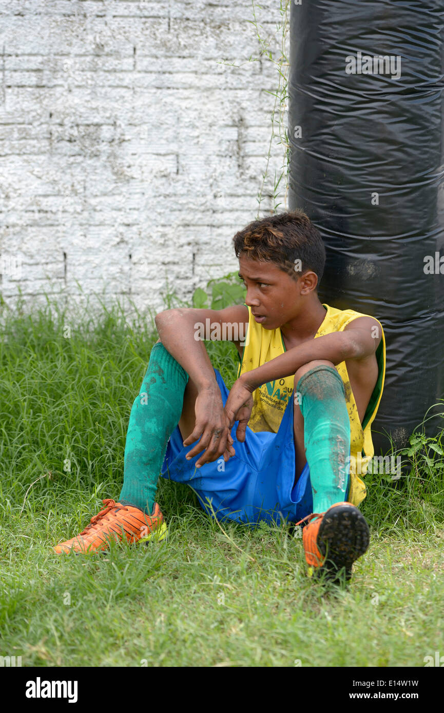Young soccer player, street child, leaning out of breath against a pole, during the preparation for the Street Children World Stock Photo