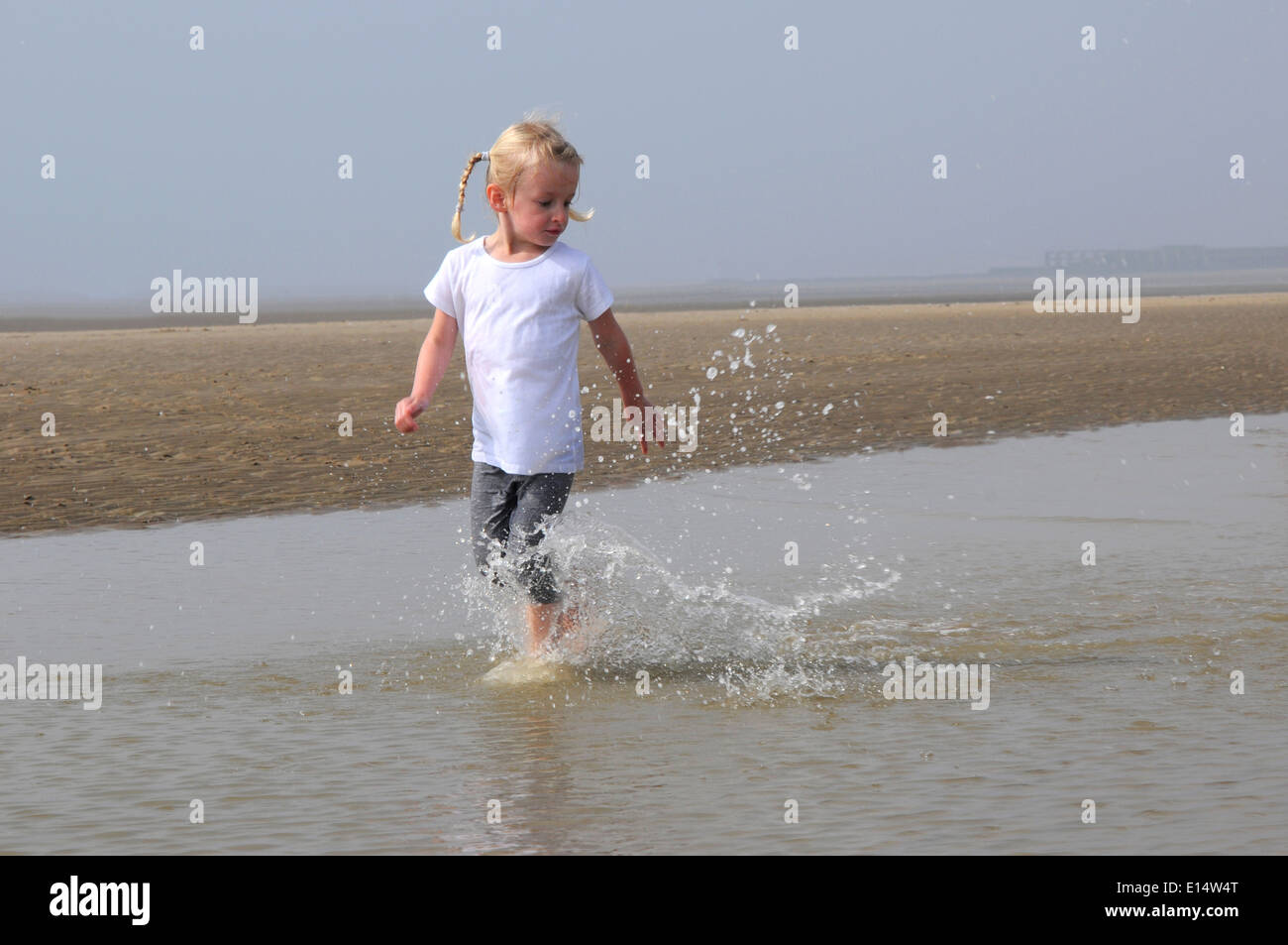 Young girl running through water on the beach Stock Photo