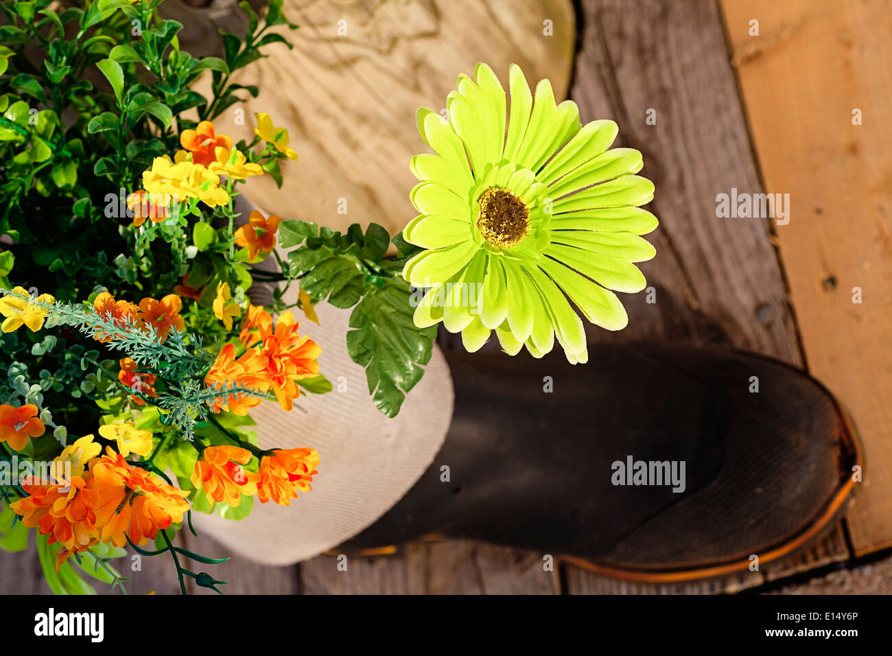 Silk flowers in a rubber boot garden. Stock Photo