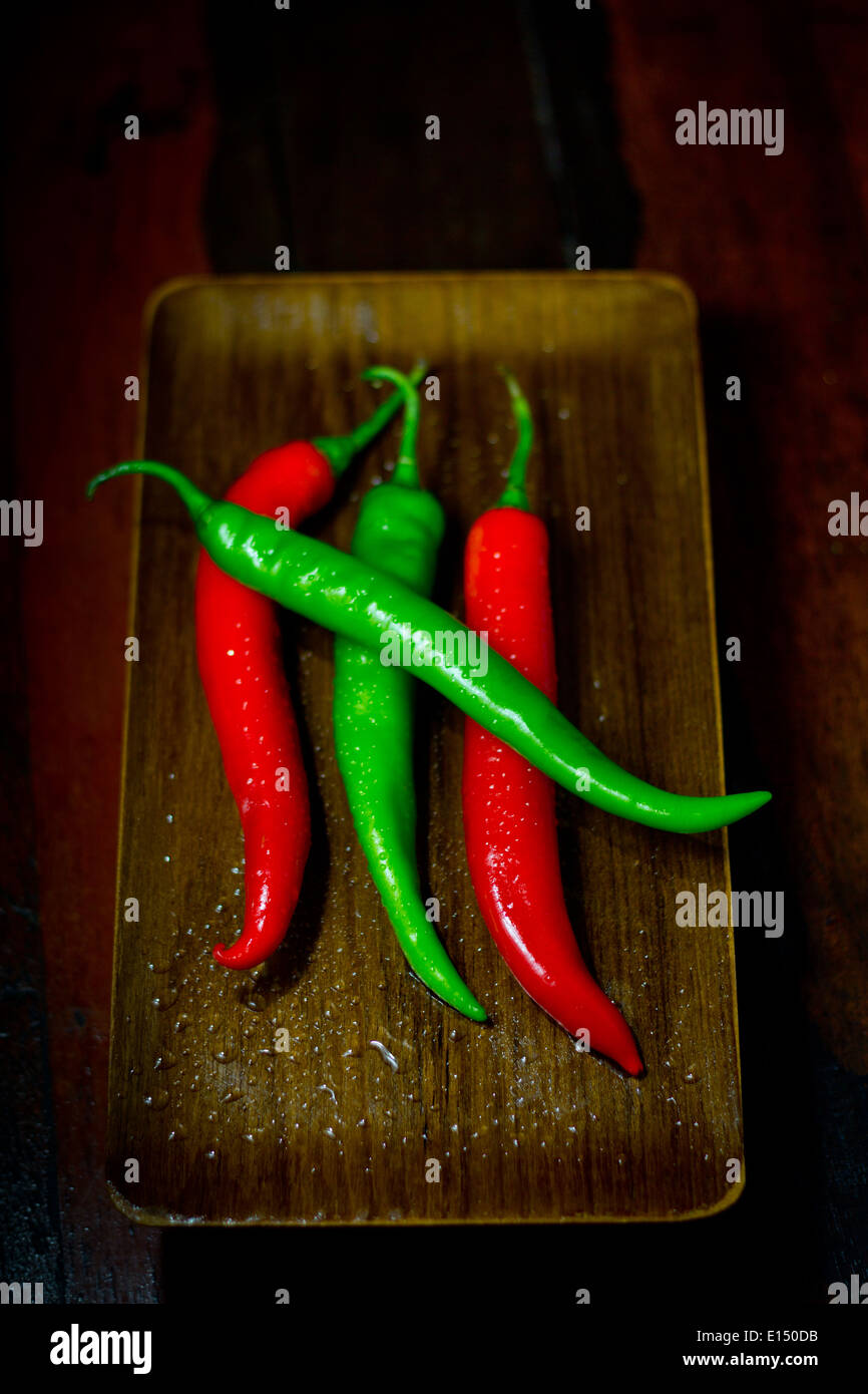 fresh [four 4 pods deep red green][Goat Horn Hot Pepper][Cayenne Pepper] on wood wooden shellac tray lay laid [on top] Stock Photo