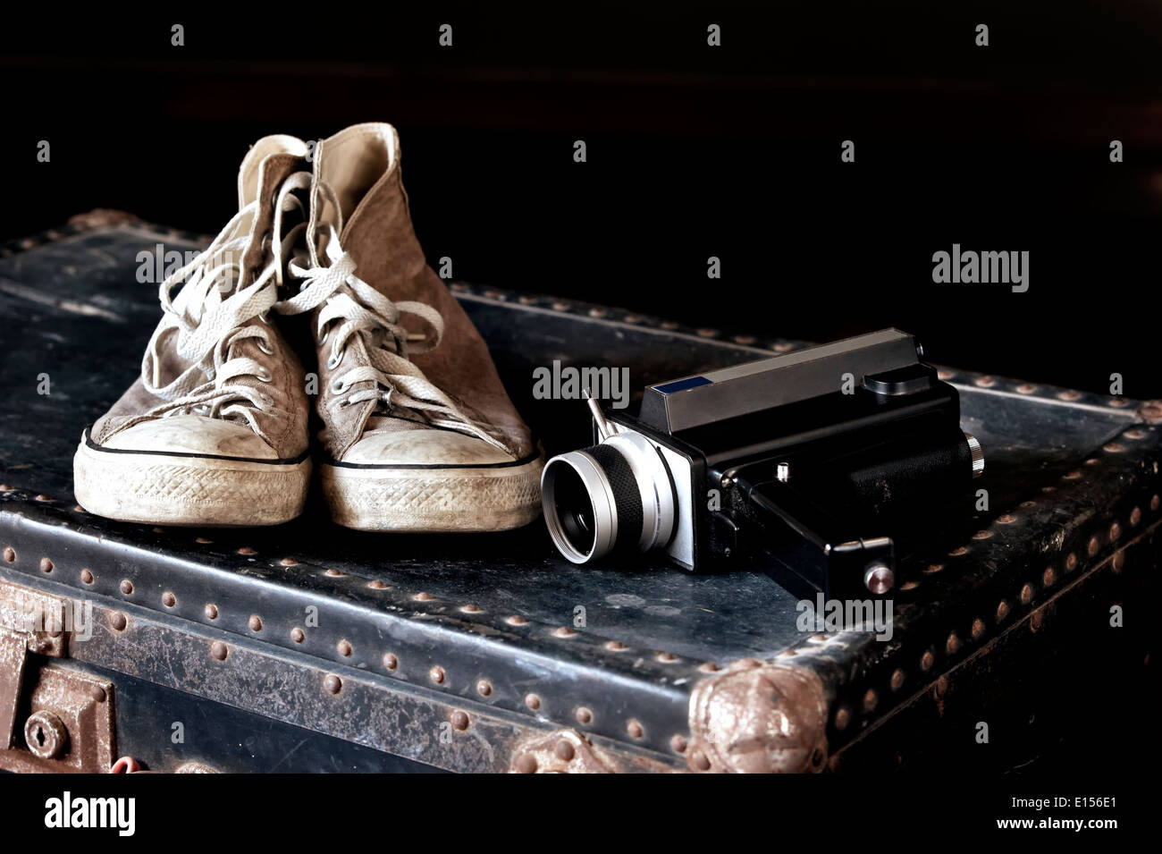 Pair of sneakers and old movie camera on vintage suitcase Stock Photo