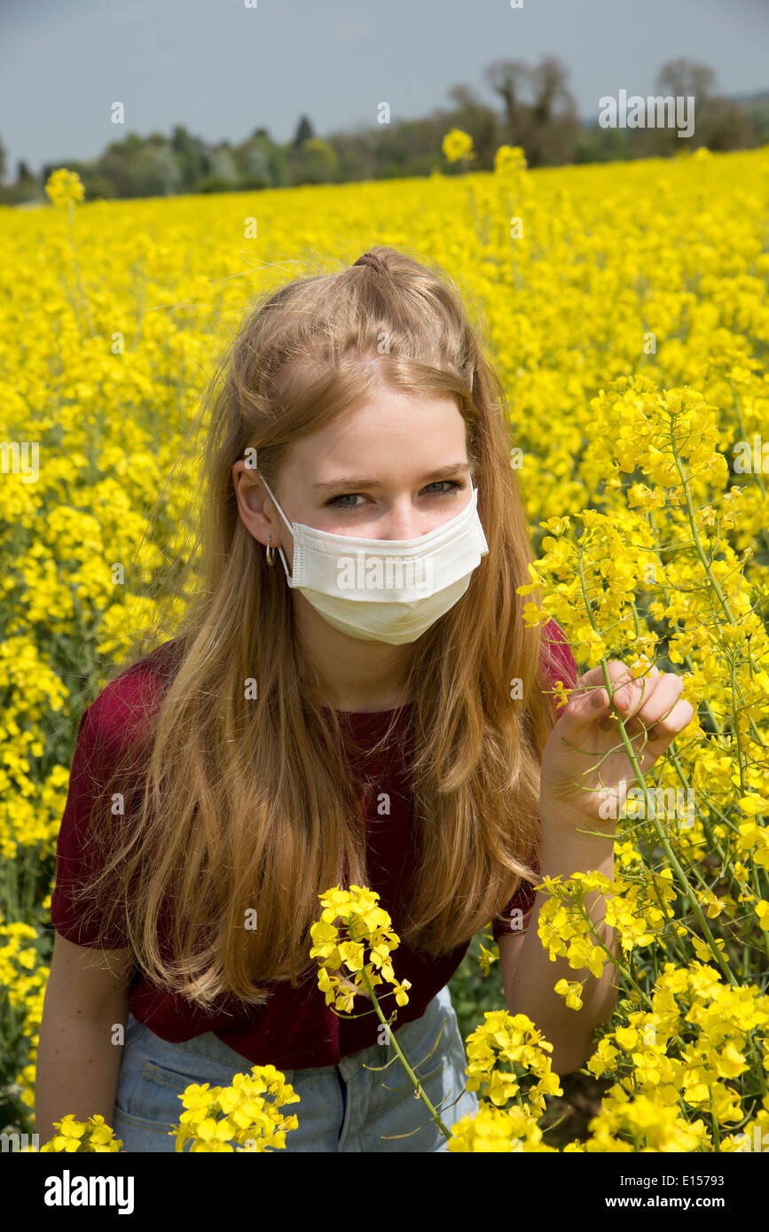 Portrait of a teenage girl in a field of rapeseed wearing a face mask allergy sufferer Stock Photo