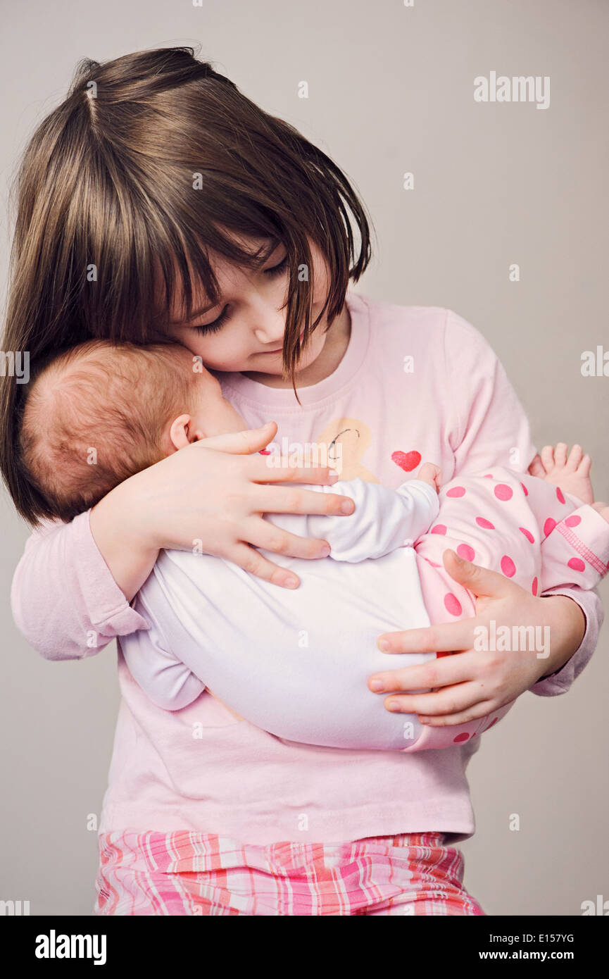 Happy girl holding her newborn sister Stock Photo