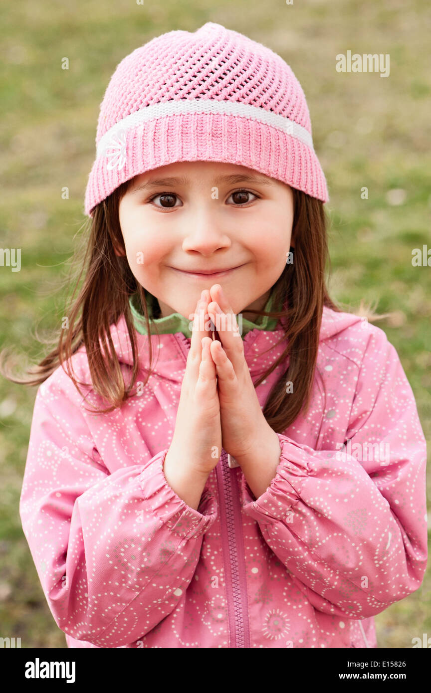 Little girl praying and smiling - closeup in the park Stock Photo