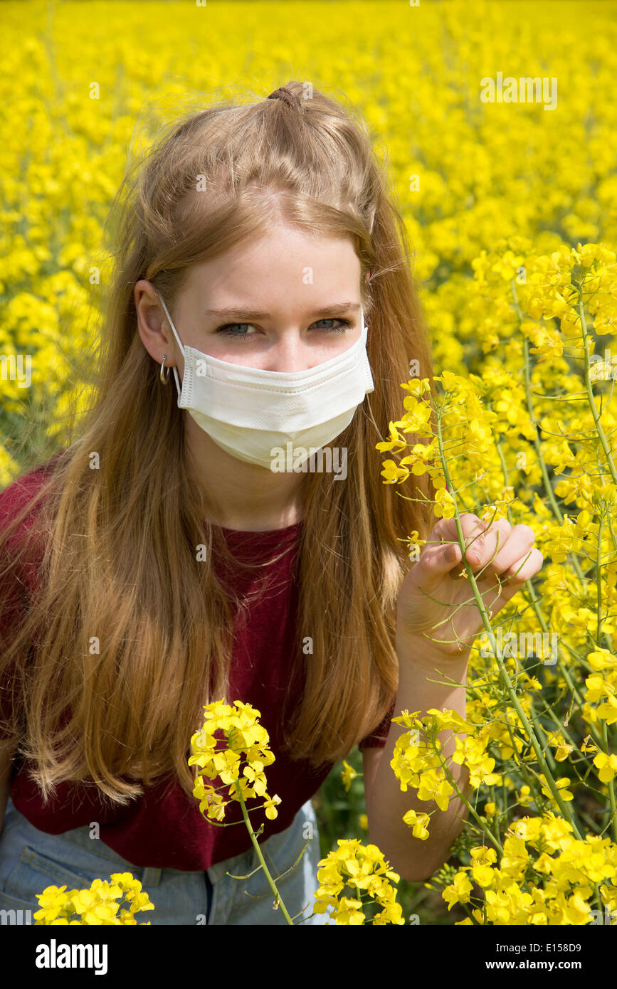 Portrait of a teenage girl in a field of rapeseed wearing a face mask allergy sufferer Stock Photo