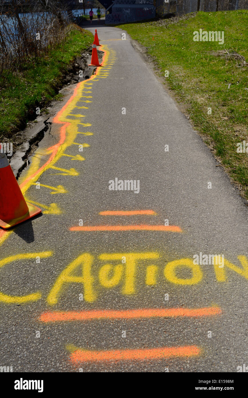 Caution spray painted on the crumbling Don River Valley bike path in Riverdale Toronto Stock Photo
