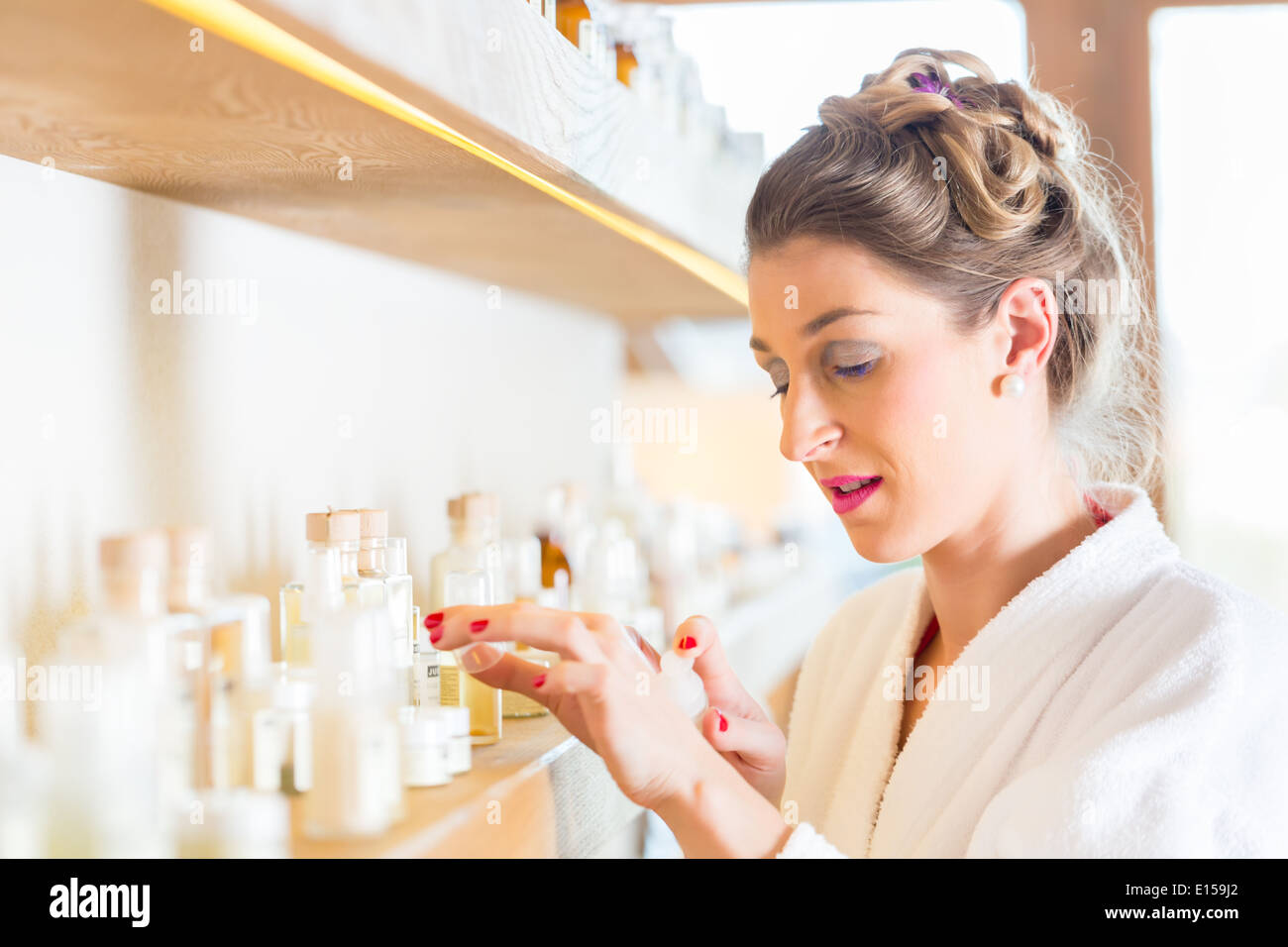 Woman in bath robe choosing face care products in wellness spa Stock Photo