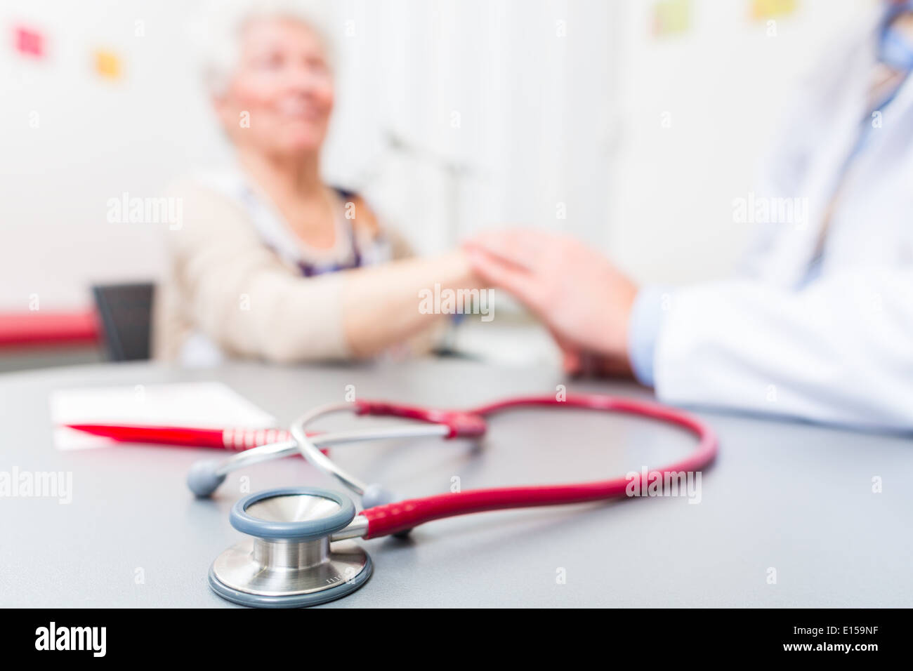 Doctor sitting with pensioner in surgery consultation hour at desk Stock Photo