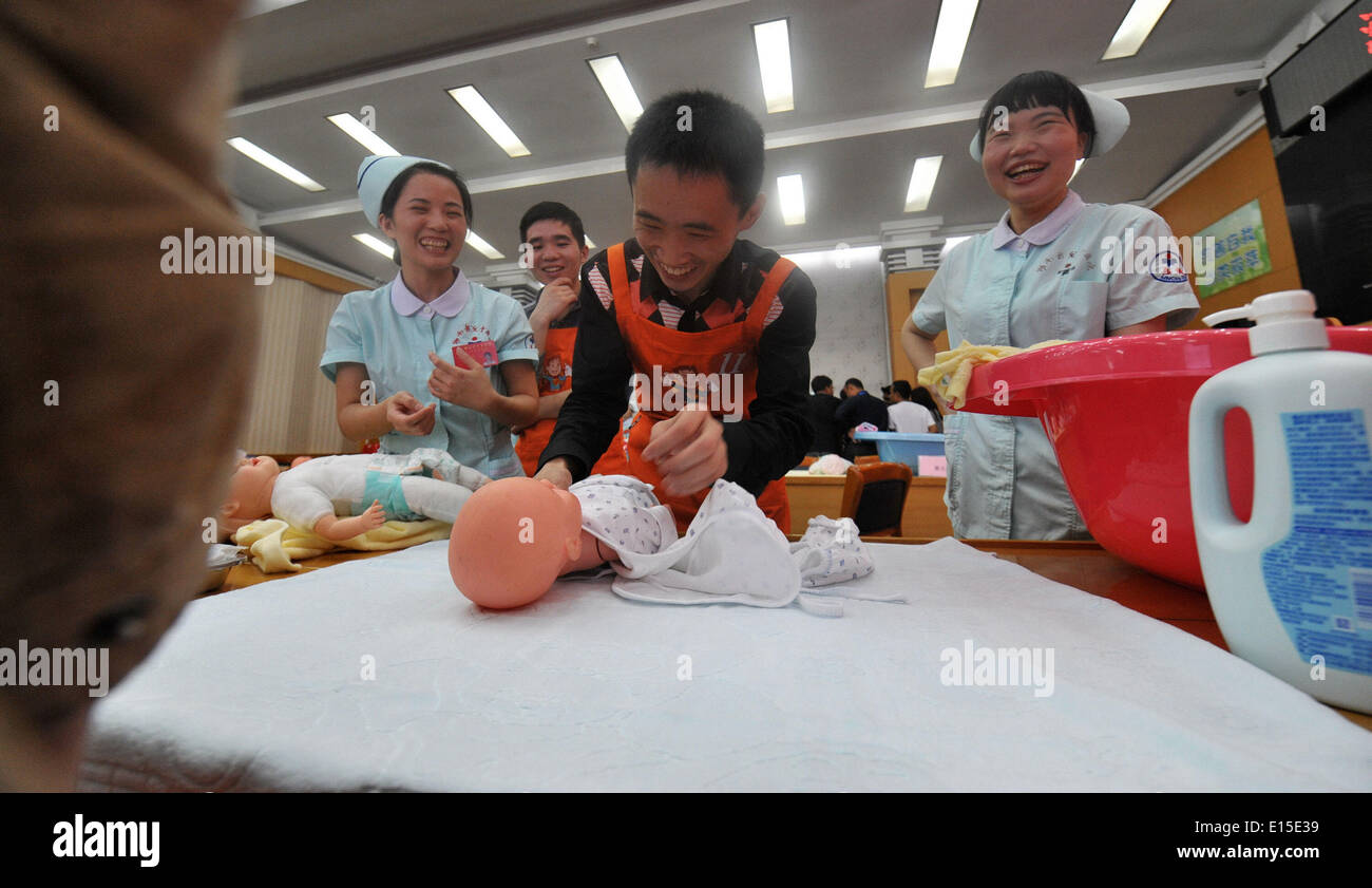 Changsha, China's Hunan Province. 23rd May, 2014. A father learns dressing a baby at a Super Daddy Training Camp at Hunan Provincial Children Hospital in Changsha, capital of central China's Hunan Province, May 23, 2014. A total of 40 daddies took part in the camp and they would learn baby nurturing skills in a short time under the guidance of paediatricians. © Long Hongtao/Xinhua/Alamy Live News Stock Photo