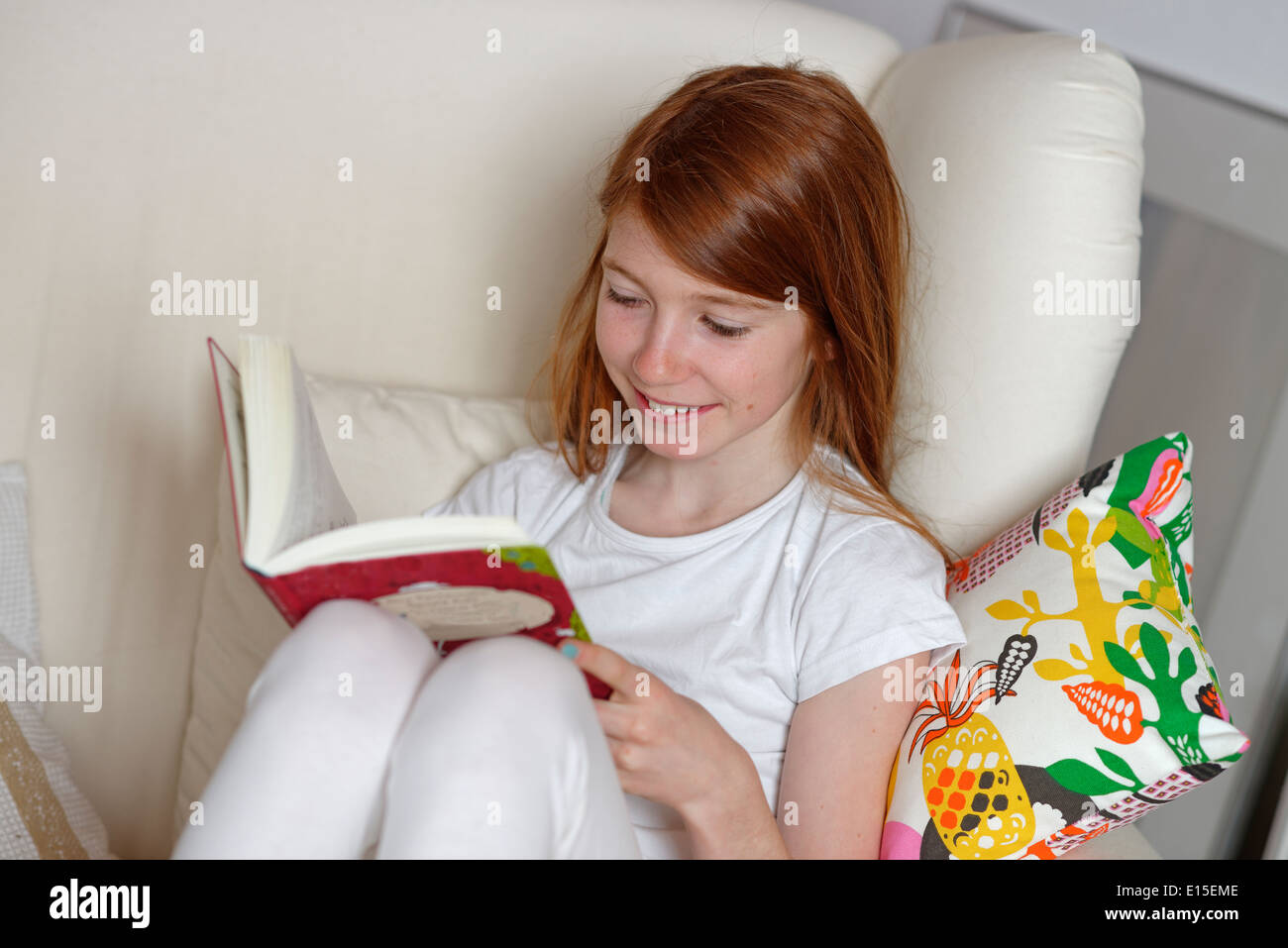 Girl sitting on sofa reading a book Stock Photo Alamy