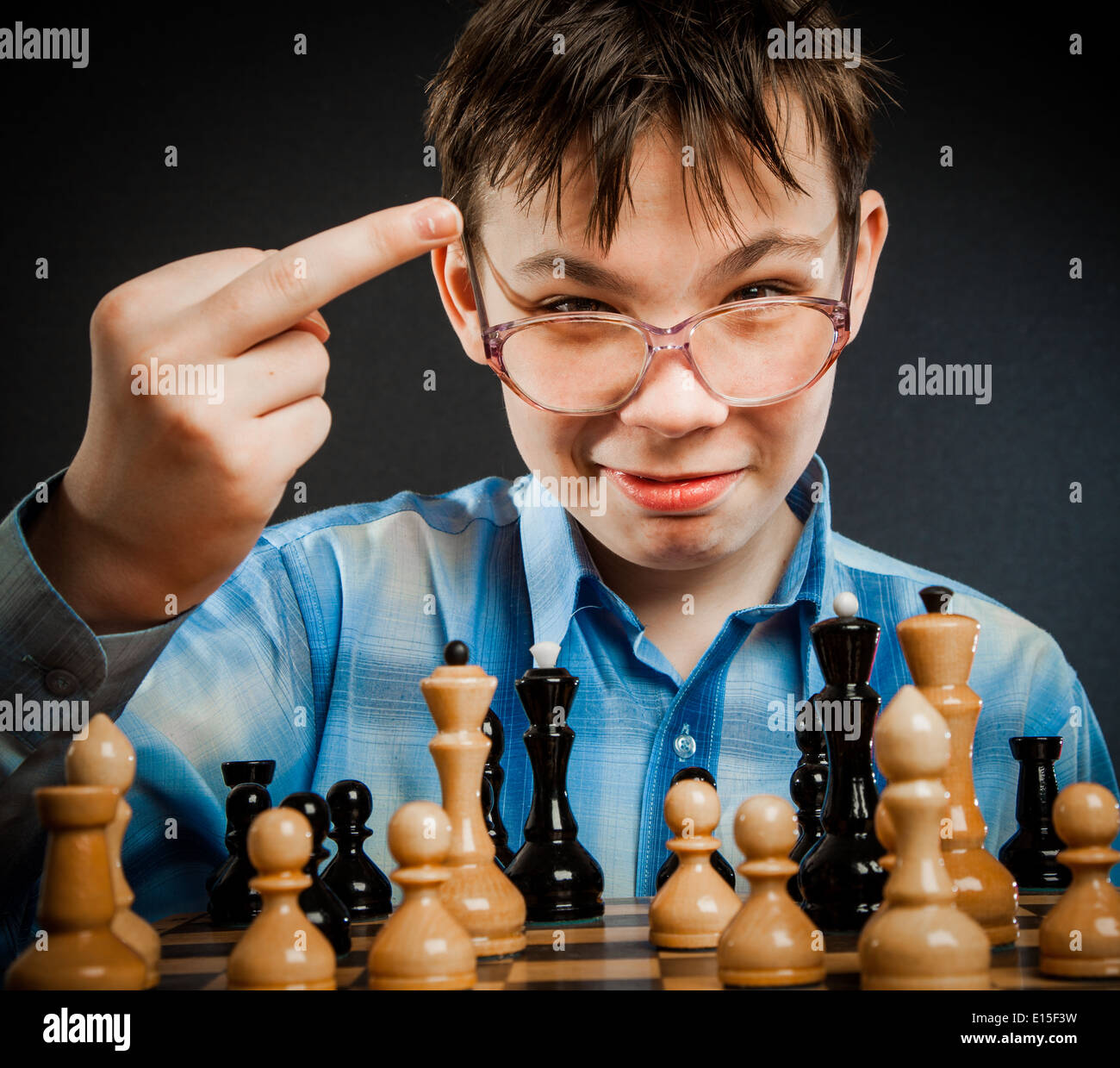 Wunderkind play chess. Funny Nerd boy. Shows the middle finger to the opponent. Stock Photo