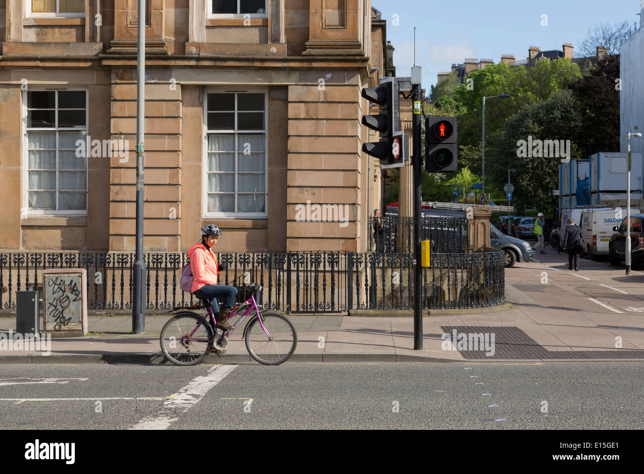 A girl/woman waiting at traffic lights (UK) on a bicycle. Stock Photo