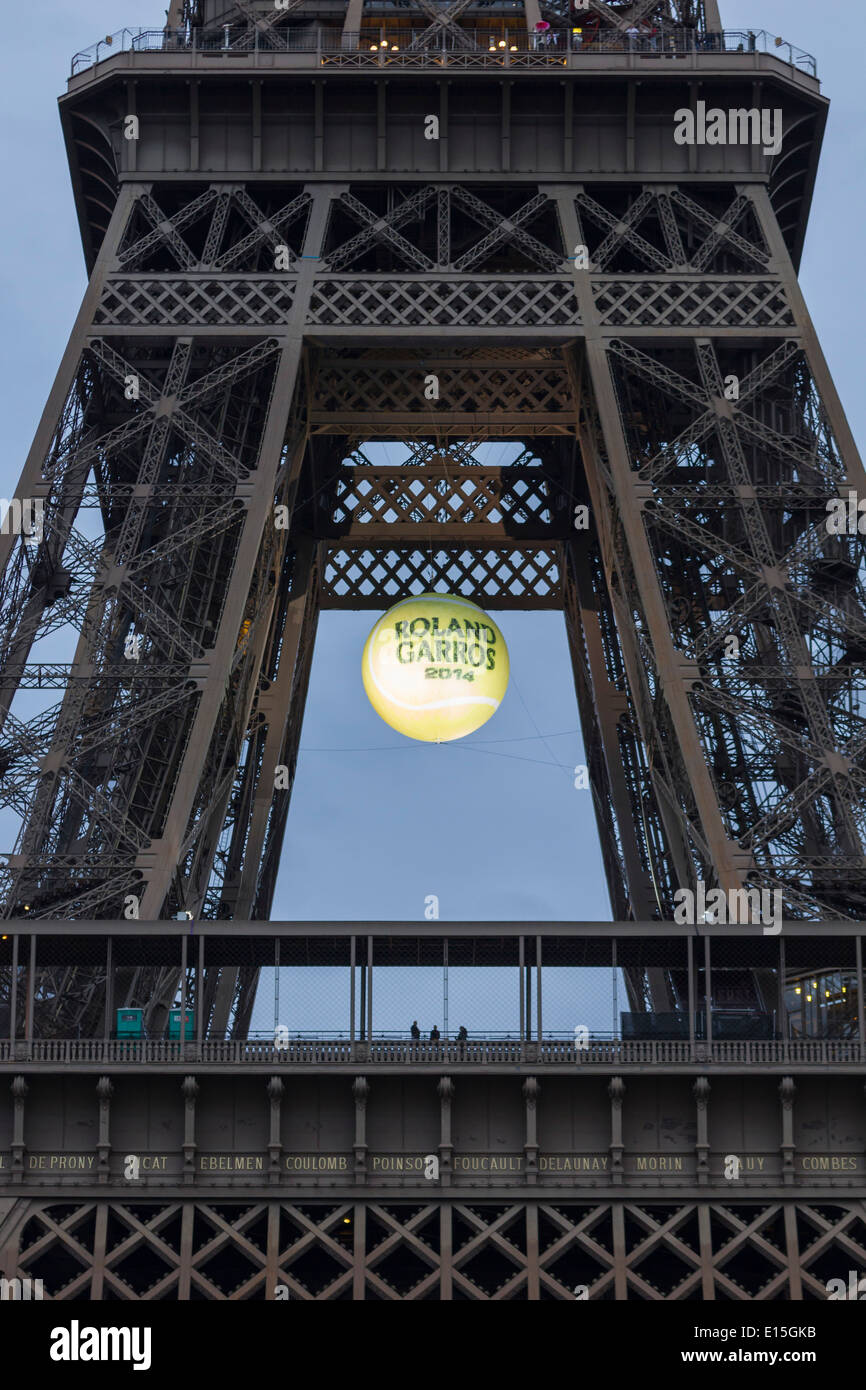 Eiffel Tower at sunset with a giant, illuminated tennis ball hanging over the first platform to promote the 2014 French Open. Stock Photo