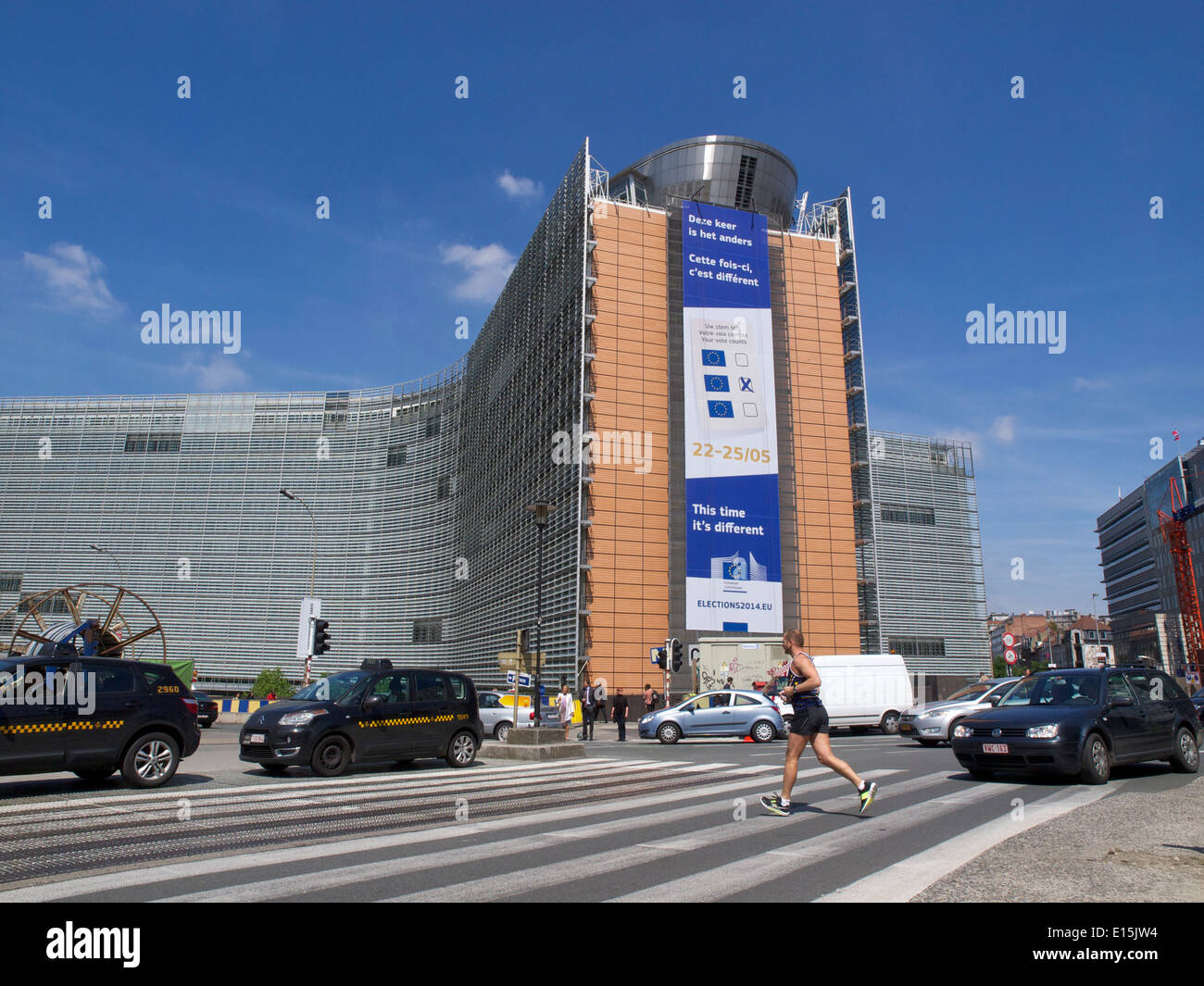 European Commission berlaymont building with runner crossing the street and parked taxis, Brussels, Belgium Stock Photo