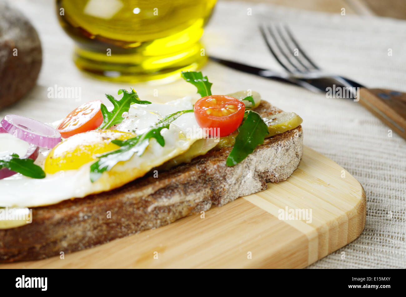 Fried egg and greens open sandwich on the cut board Stock Photo