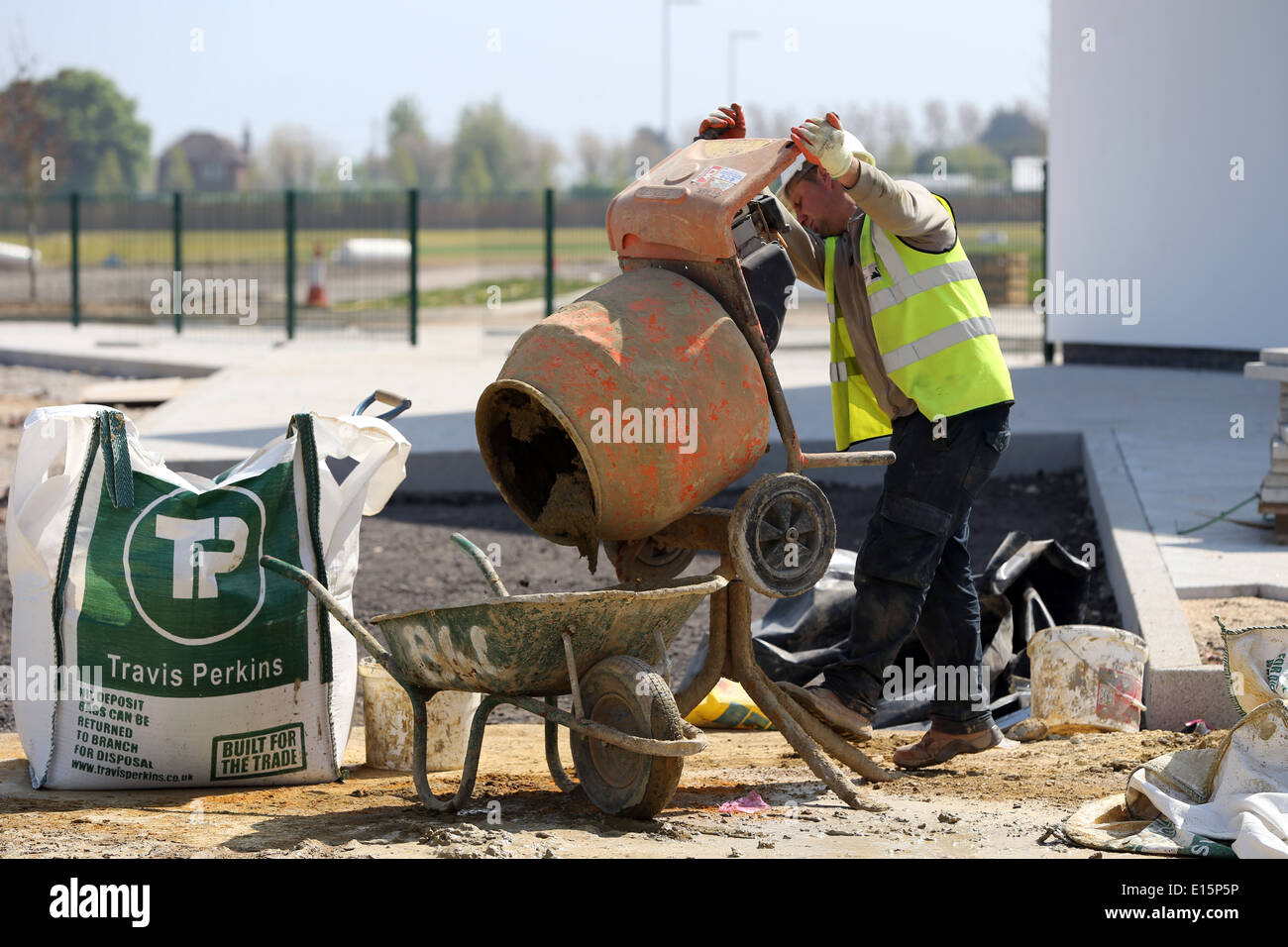 Tradesman, workman cement mixer pouring cement into a wheel barrow. Travis Perkins Stock Photo