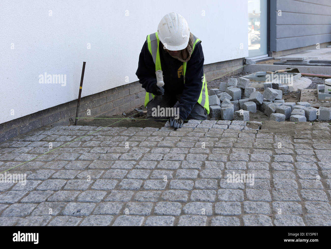 Tradesman workman building site laying paving slabs cobblestones Stock Photo
