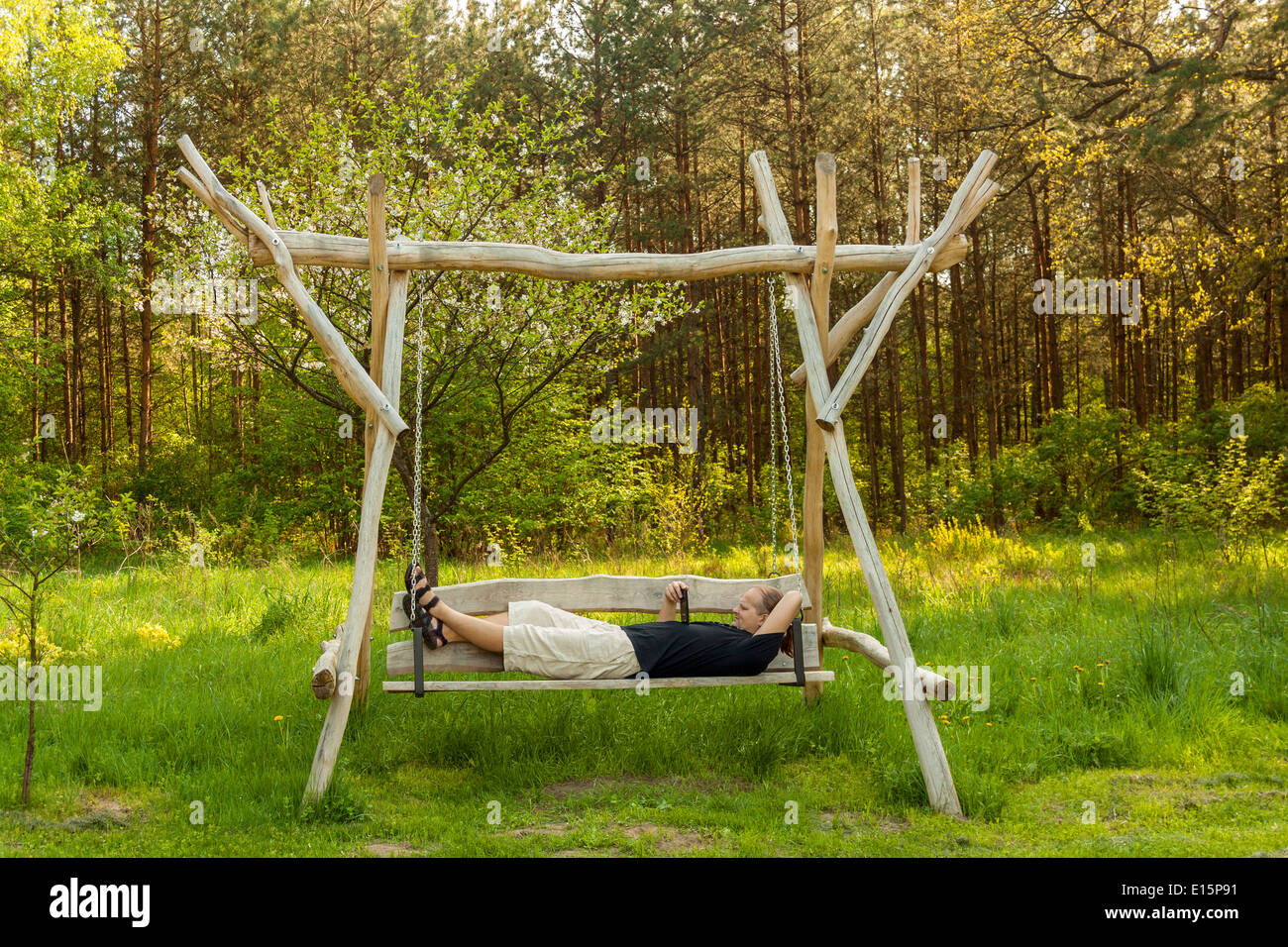 Adult man reading an ebook why lying on a swing Stock Photo