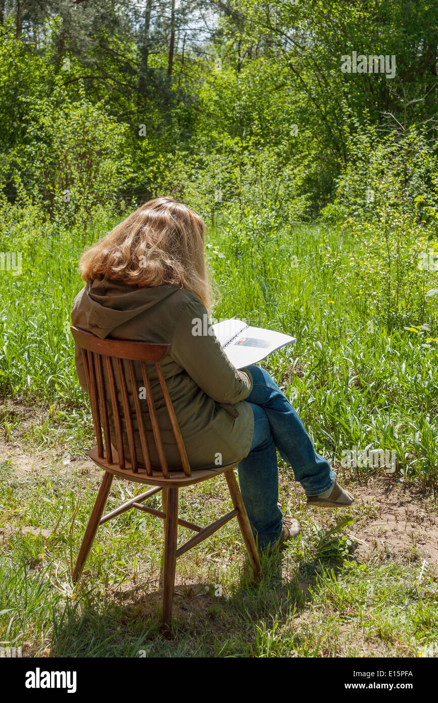 Woman sitting outdoors on a chair and reading Stock Photo - Alamy
