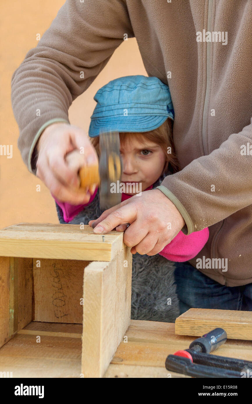 Father and daughter hitting nails to build birdhouse Stock Photo