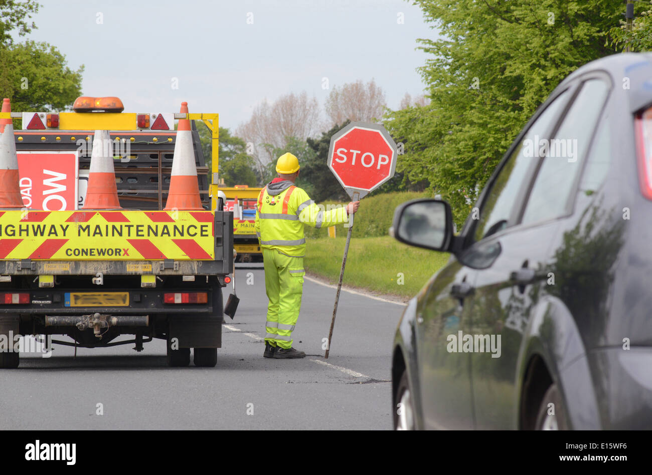 construction worker using lollipop stop - go sign to control traffic at roadworks united kingdom Stock Photo