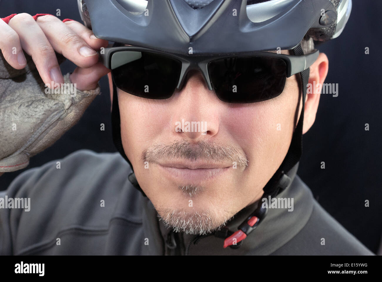 Close-up of a friendly bicycle courier putting on his sunglasses. Stock Photo