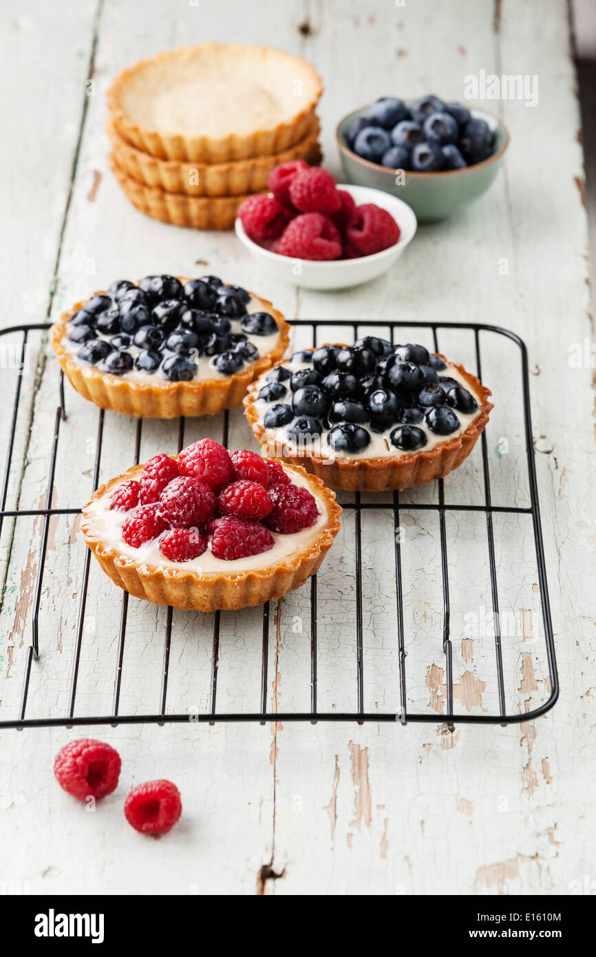 Tartlets with fresh raspberries and blueberries on cooling rack Stock Photo