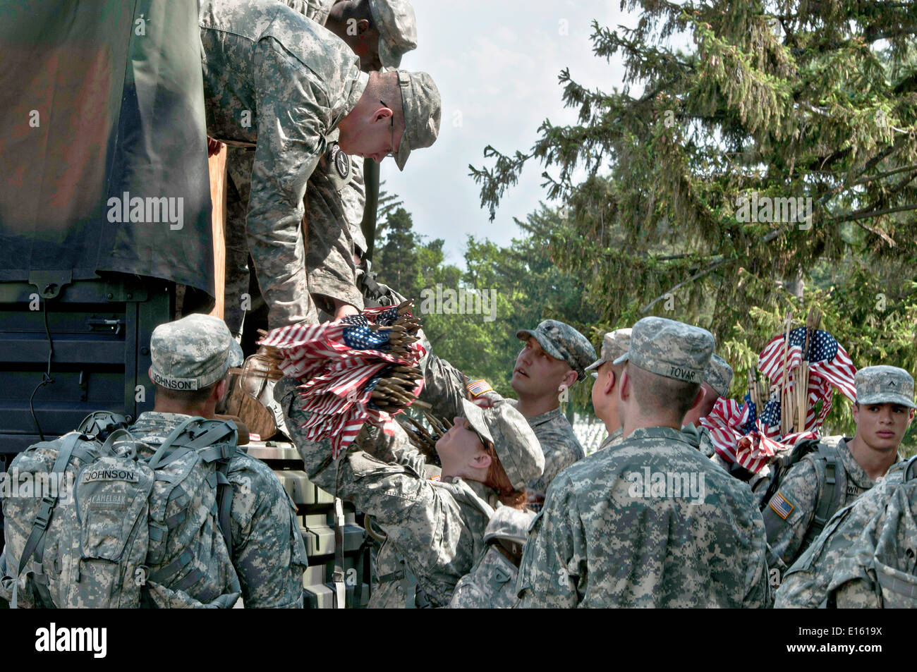 US Army soldier from the Old Guard distribute flags to be placed in front of grave sites in honor of Memorial Day at Arlington National Cemetery May 22, 2014 in Arlington, Virginia. Stock Photo