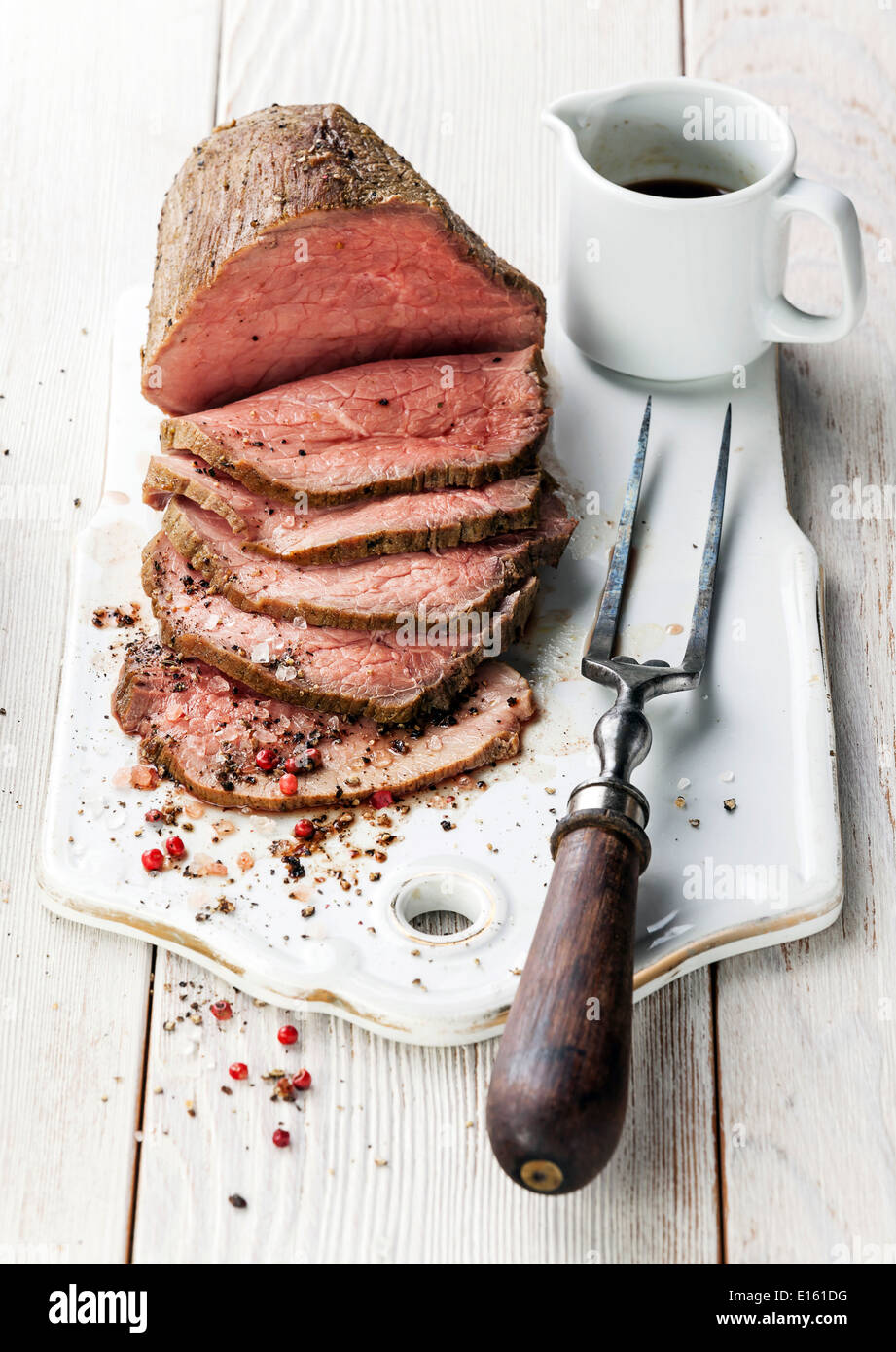 Roast beef with sauce and meat fork on white wooden background Stock Photo