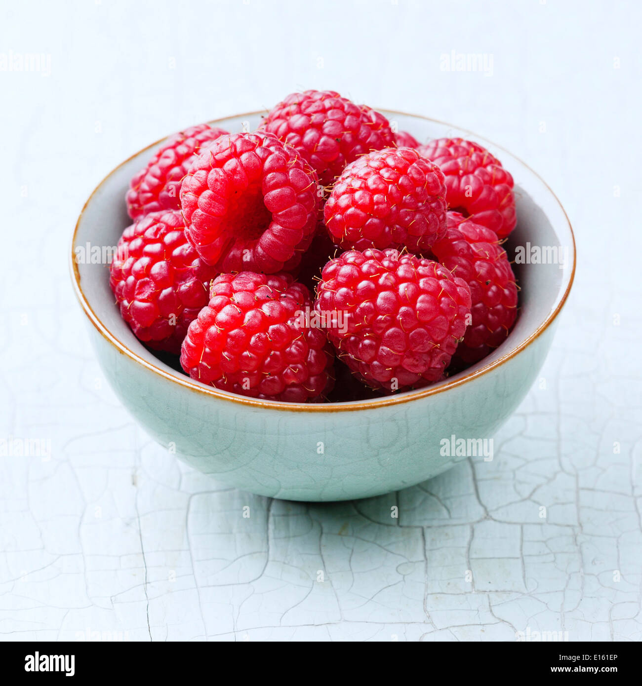 Raspberries in bowl on blue background Stock Photo