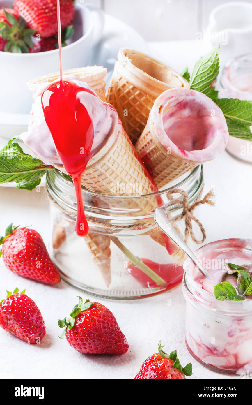 Wafer cones with strawberry ice cream with pouring syrup and fresh ...