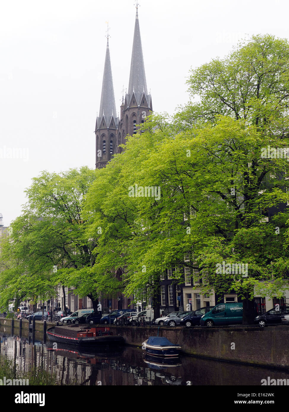 Two Cathedral Steeples Rising Above Amsterdam Canal Stock Photo