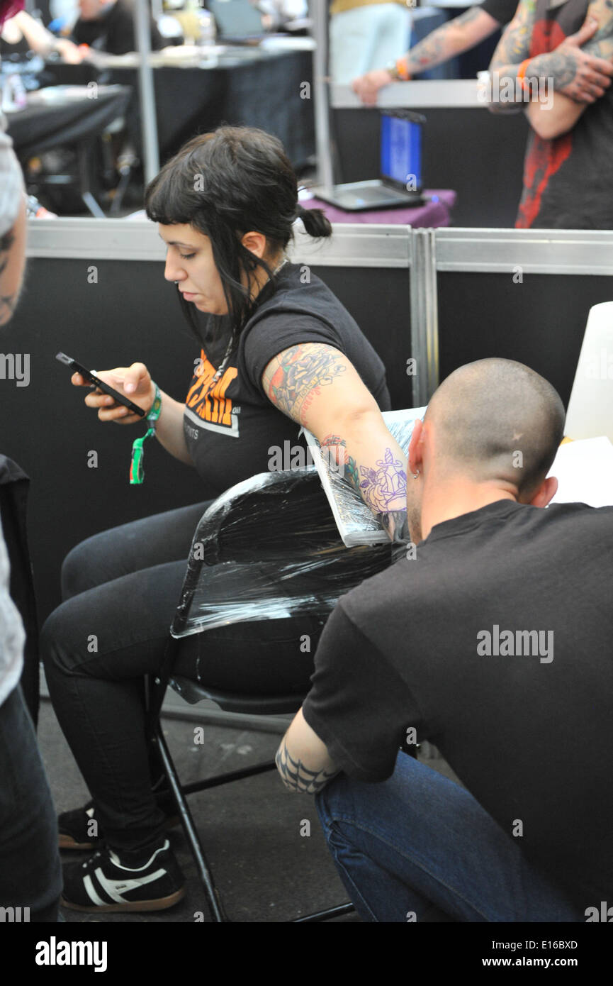 Alexandra Palace, London, UK. 24th May 2014. A tattoo artist at work on a womans arm at the Great British Tattoo Show taking place this weekend at Alexandra Palace. The show features tattooing,  stall selling clothing and accessories, wrestling and a fashion show Credit:  Matthew Chattle/Alamy Live News Stock Photo