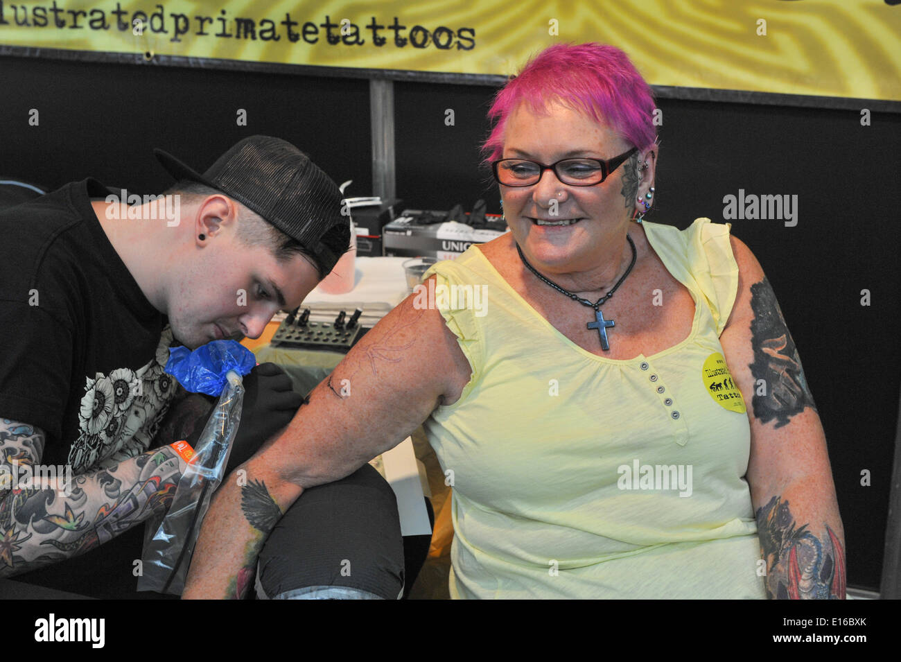 Alexandra Palace, London, UK. 24th May 2014. A tattoo artist at work on a womans arm at the Great British Tattoo Show taking place this weekend at Alexandra Palace. The show features tattooing,  stall selling clothing and accessories, wrestling and a fashion show Credit:  Matthew Chattle/Alamy Live News Stock Photo