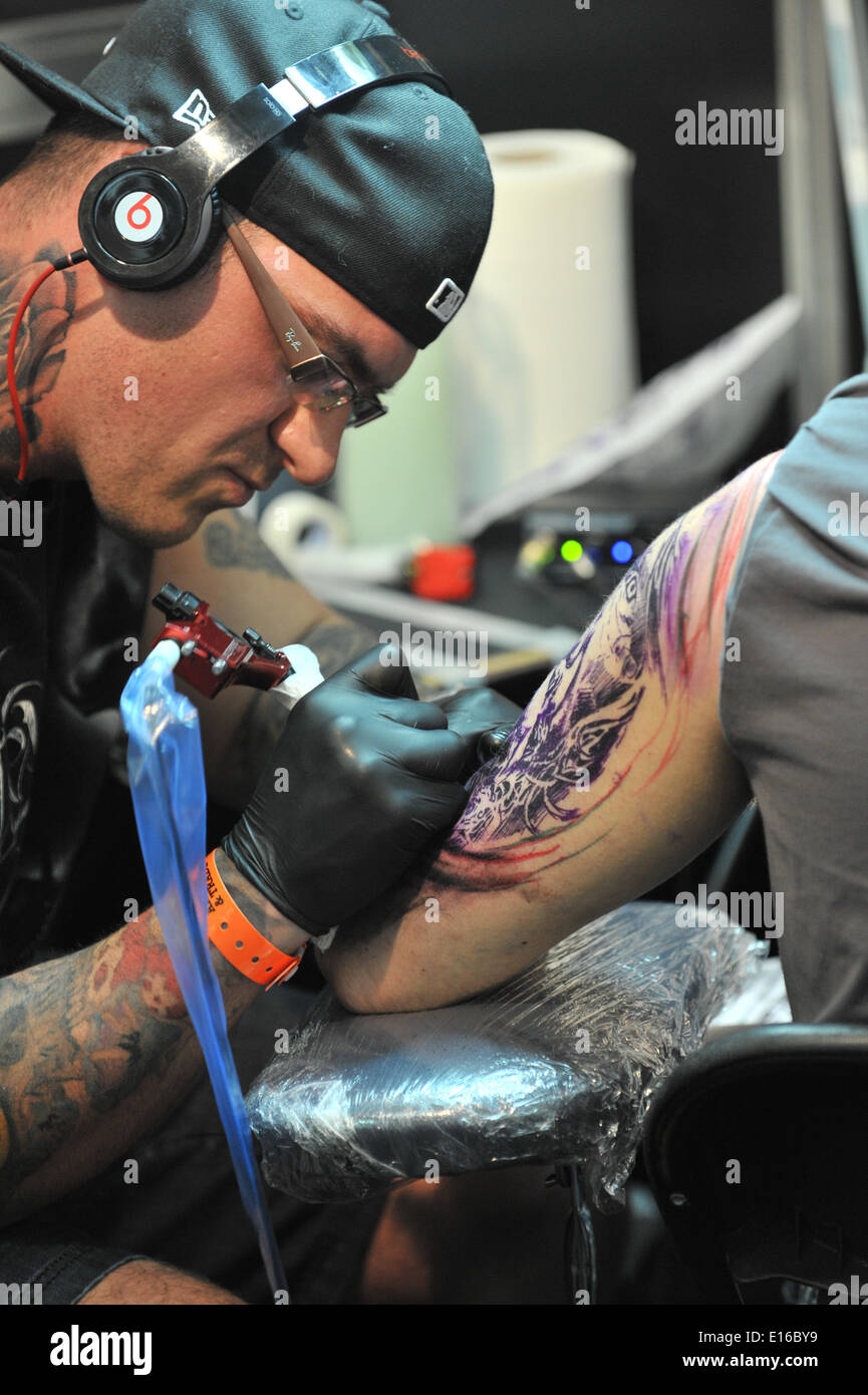 Alexandra Palace, London, UK. 24th May 2014. Tattooing a mans shoulder at the Great British Tattoo Show taking place this weekend at Alexandra Palace. The show features tattooing,  stall selling clothing and accessories, wrestling and a fashion show Credit:  Matthew Chattle/Alamy Live News Stock Photo