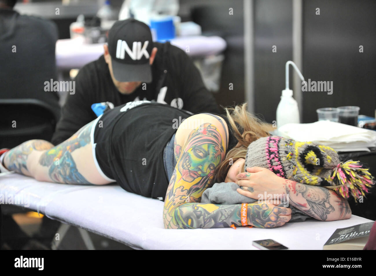 Alexandra Palace, London, UK. 24th May 2014. Tattooing a womans leg at the Great British Tattoo Show taking place this weekend at Alexandra Palace. The show features tattooing,  stall selling clothing and accessories, wrestling and a fashion show Credit:  Matthew Chattle/Alamy Live News Stock Photo