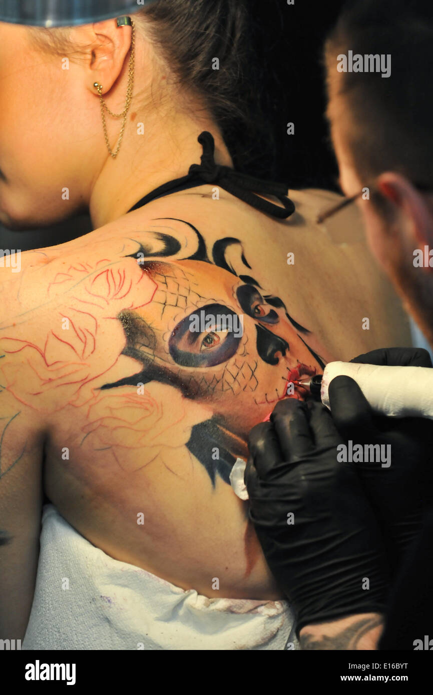 Alexandra Palace, London, UK. 24th May 2014. Tattooing a womans shoulder at the Great British Tattoo Show taking place this weekend at Alexandra Palace. The show features tattooing,  stall selling clothing and accessories, wrestling and a fashion show Credit:  Matthew Chattle/Alamy Live News Stock Photo