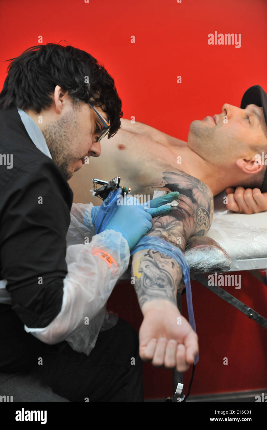 Alexandra Palace, London, UK. 24th May 2014. Tattooing a mans arm at the Great British Tattoo Show taking place this weekend at Alexandra Palace. The show features tattooing,  stall selling clothing and accessories, wrestling and a fashion show Credit:  Matthew Chattle/Alamy Live News Stock Photo