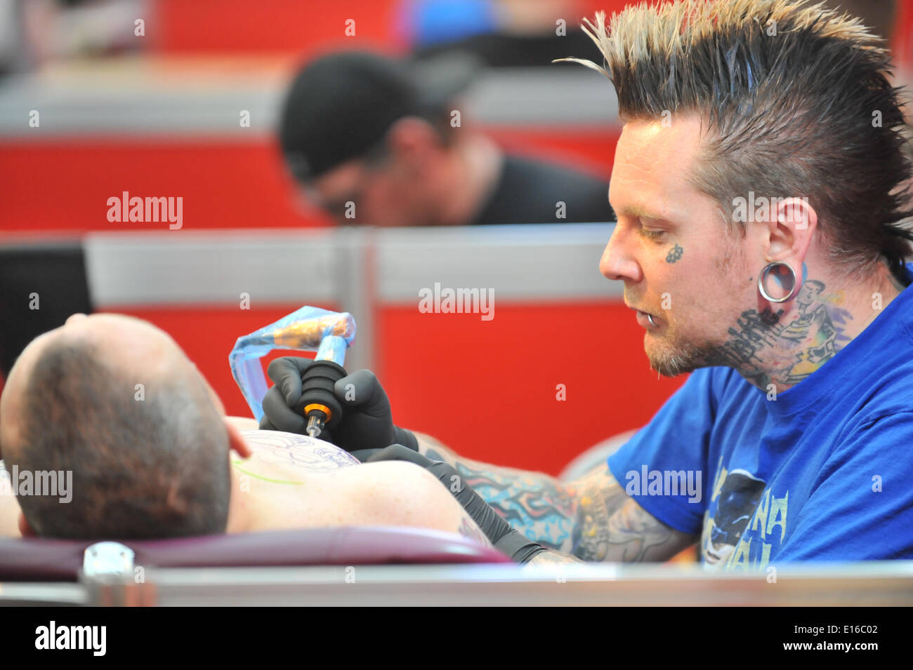 Alexandra Palace, London, UK. 24th May 2014. A tattoist concentrates on his work at the Great British Tattoo Show taking place this weekend at Alexandra Palace. The show features tattooing,  stall selling clothing and accessories, wrestling and a fashion show Credit:  Matthew Chattle/Alamy Live News Stock Photo